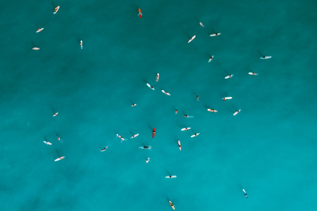 aerial shot capturing surfers on turquoise ocean water emphasizing out