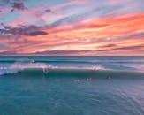 五颜六色的日落与冲浪者在海洋中，戏剧性的天空为场景增添了活力