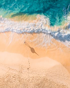 从鸟瞰图可以看到，一个宁静的海滩上，沙滩布满充满活力的波浪和脚印