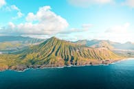 从空中俯瞰，沿海山脉郁郁葱葱，海浪拍岸，景色壮丽