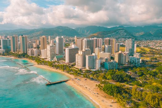 Photo by Jess Loiterton Aerial view of Waikiki Beach's pristine shoreline with the bustling Honolulu skyline in the background.