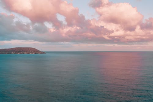 Blue Sea Near Mountain Under White Clouds