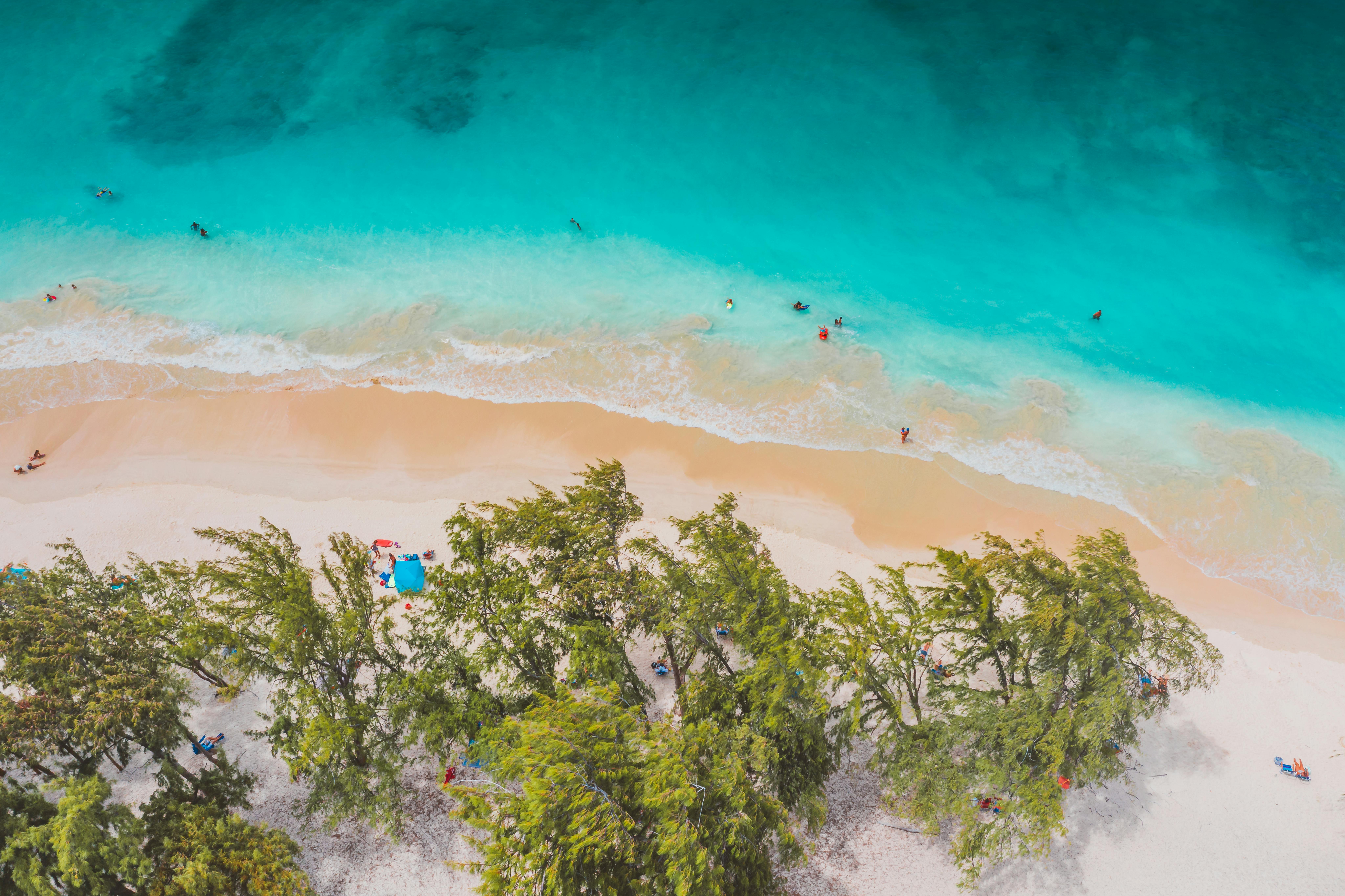 A stunning aerial shot of a tropical beach with vivid turquoise waters, sandy shore, and lush greenery.