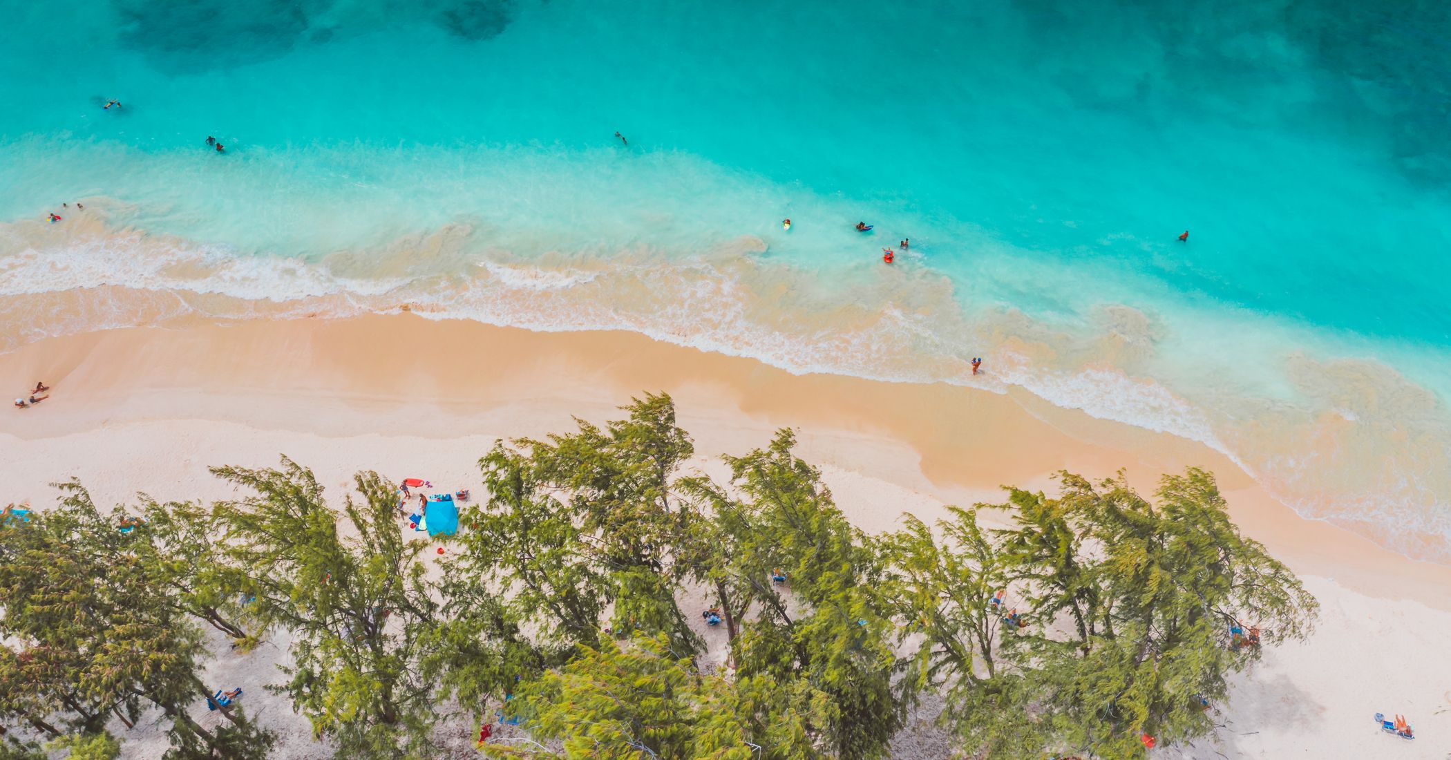 Aerial view of a turquoise shoreline wrapping around soft sand.