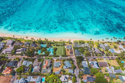 Aerial view of a tropical coastal neighborhood with blue ocean and palm trees showcasing vibrant scenery.