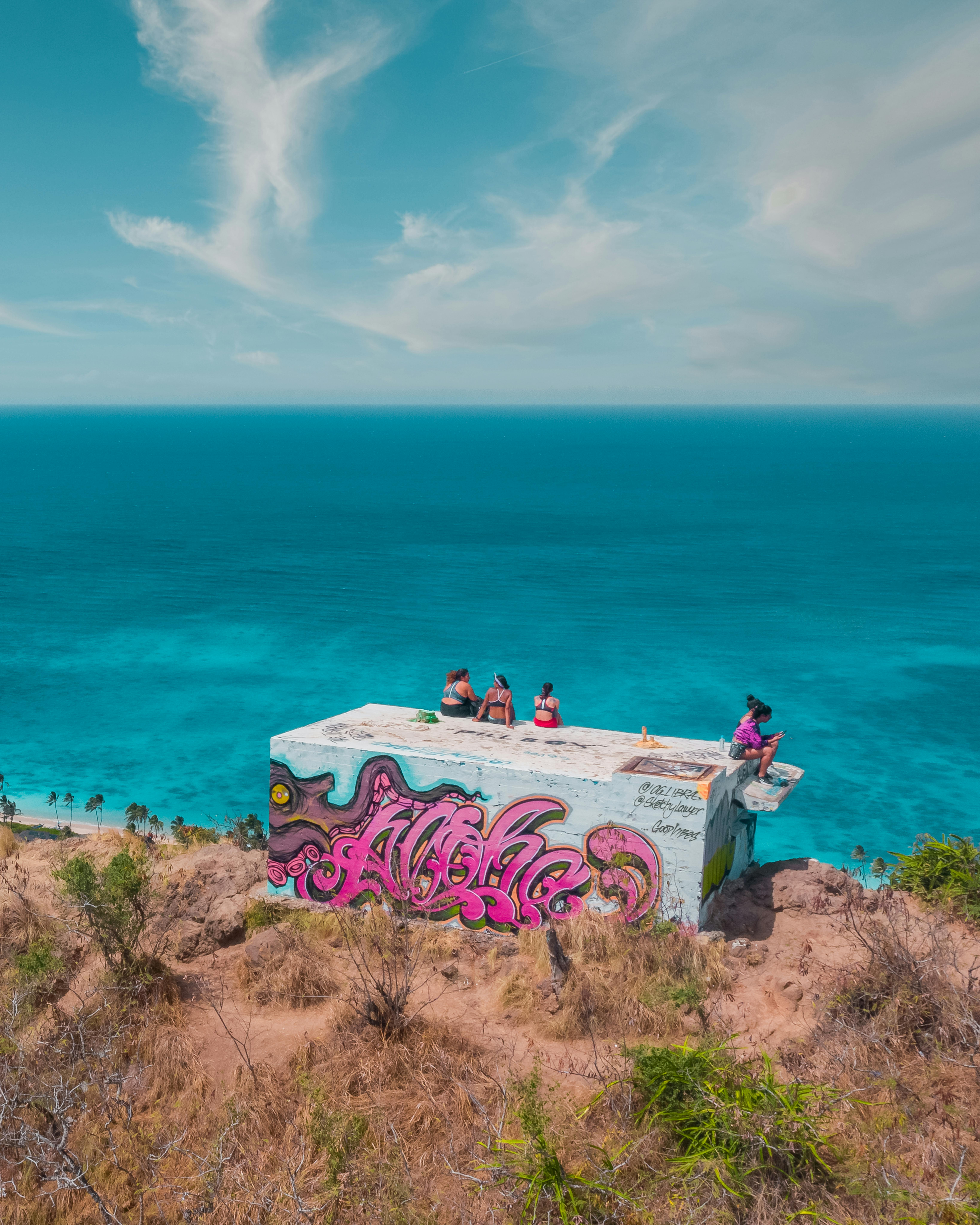 人们在涂鸦覆盖的建筑上放松，俯瞰大海的风景