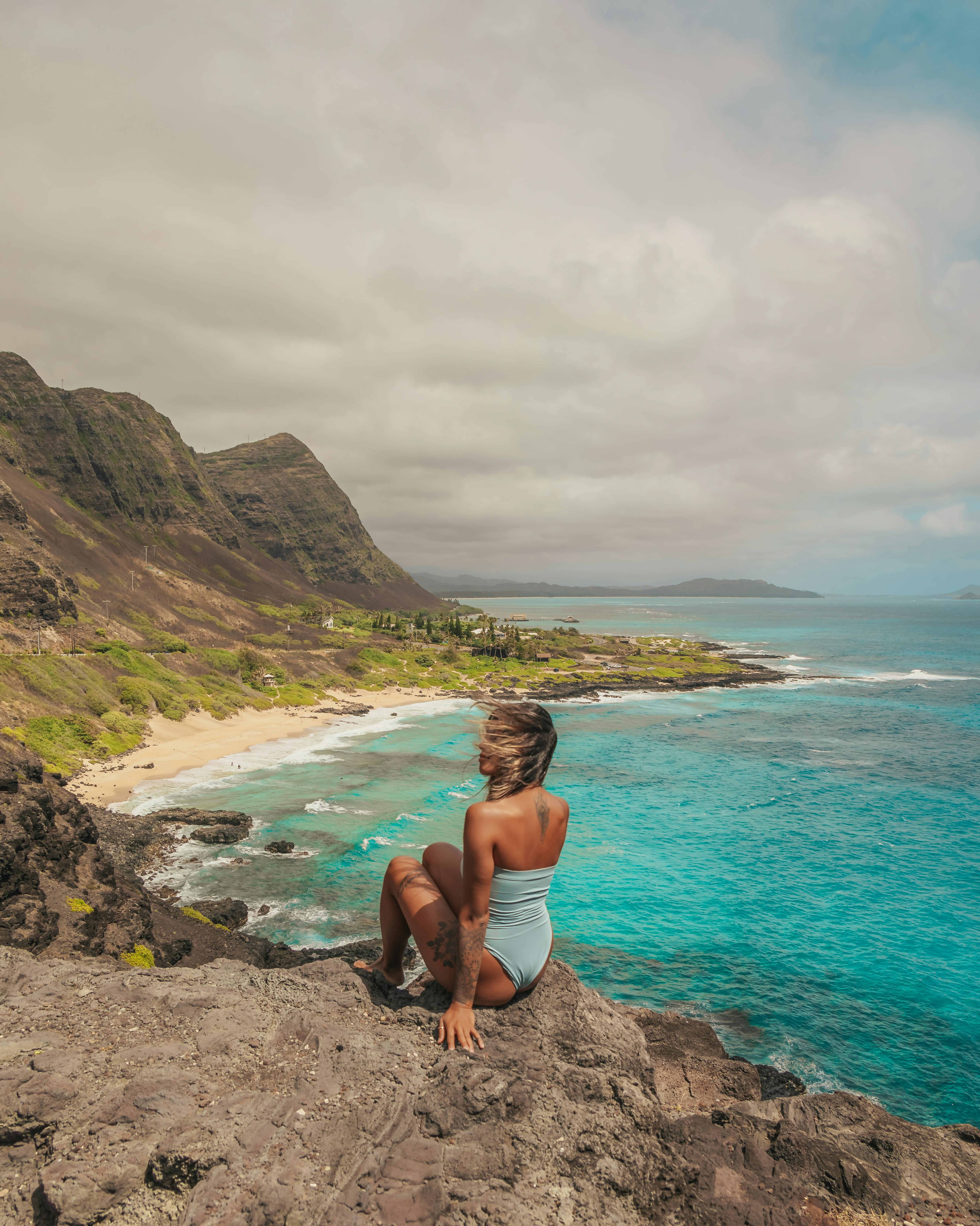 穿着泳衣的女子欣赏碧绿海水和山脉的美丽海滩景色