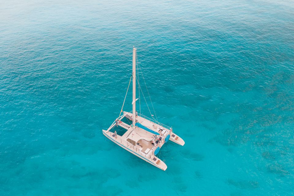 Aerial view of a white catamaran anchored over bright blue shallow water