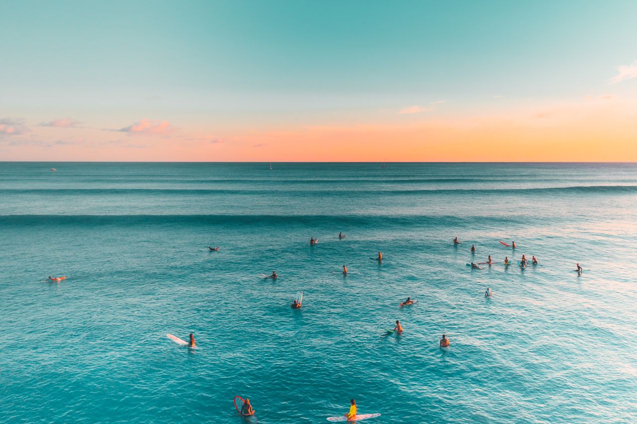 people paddleboarding in the ocean during a vibrant sunset enjoying a
