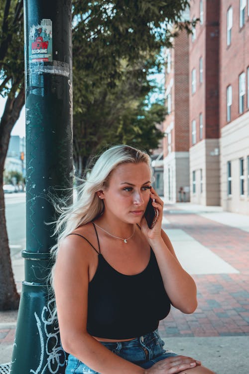 Woman in Black Tank Top Holding a Smartphone