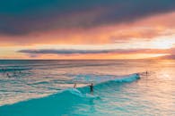 冲浪者在令人惊叹的日落天空下骑着绿松石般的波浪