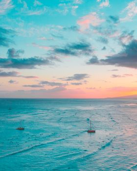 空中展现了一幅令人叹为观止的海景：充满活力的日落映照在平静的海面上，几艘船只零星散布其间