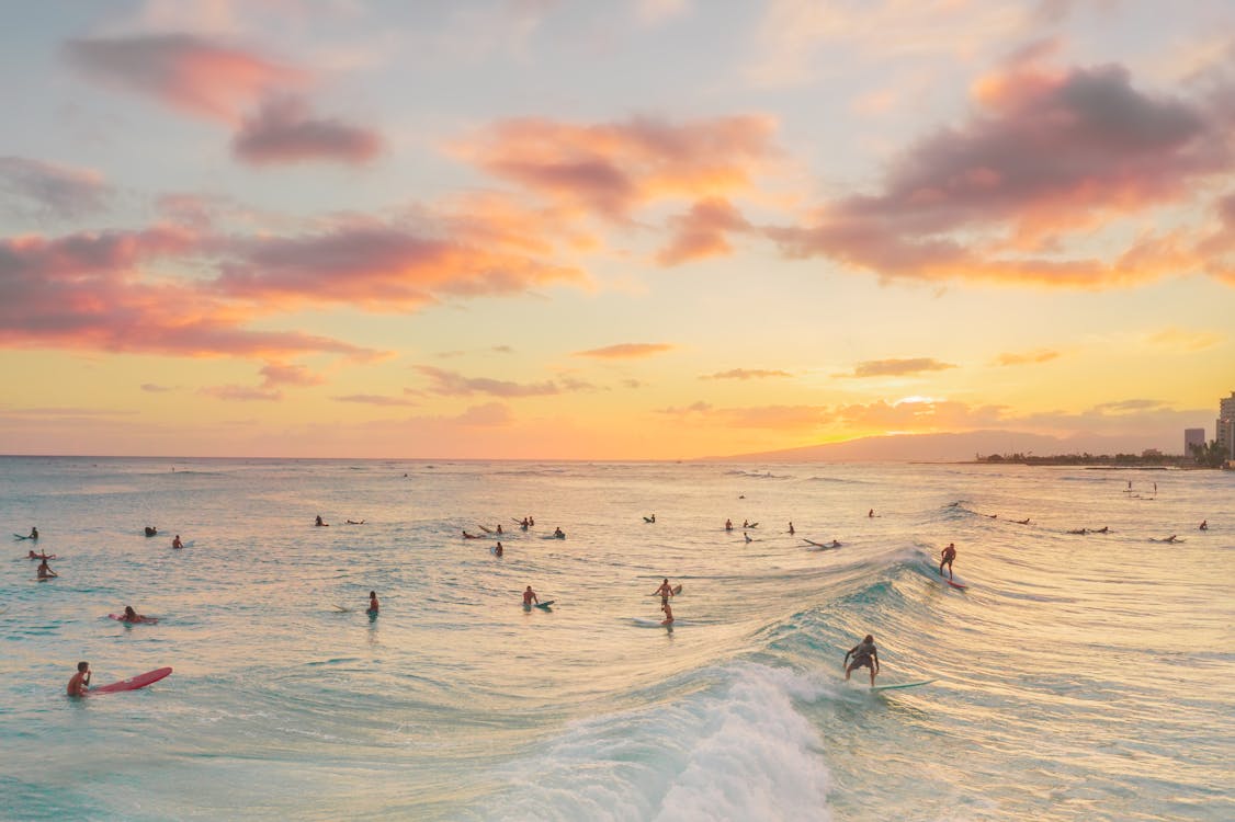 Tourists Surfing on Sea Waves during Sunset