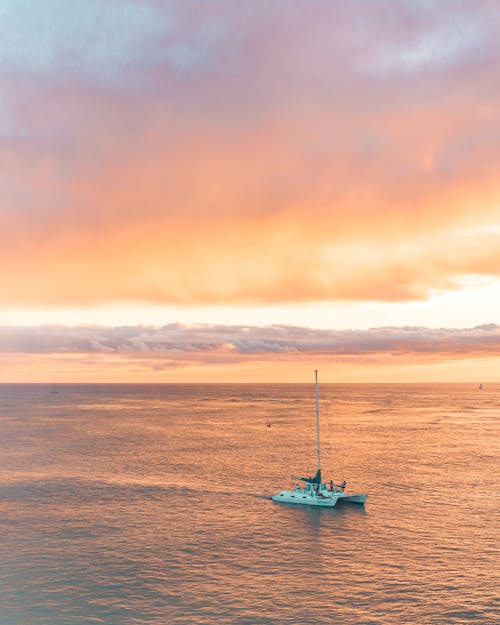 Free Aerial View of a Sailboat in the Sea during Sunset Stock Photo