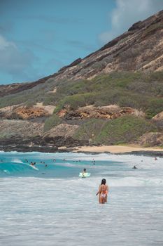 People enjoying a sunny day at a tropical beach with clear blue waters and lush green hills.