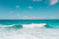 在湛蓝的天空下，冲浪者骑着碧绿的海浪，捕捉着夏季冒险的精髓