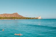 背景是钻石头，威基基海滩上冲浪者的场景充满活力