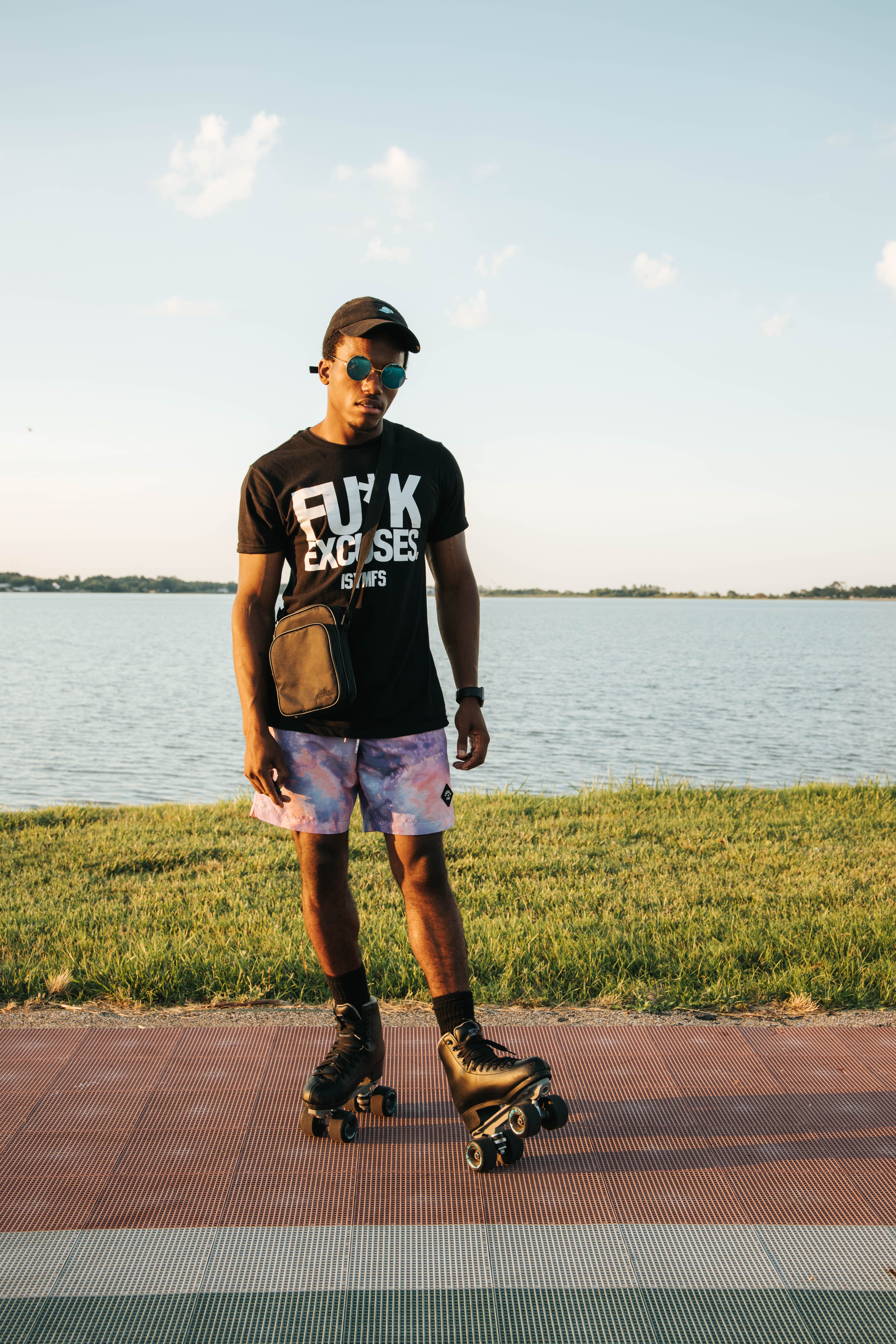 A stylish man roller skating by the water on a sunny day, embodying summer vibes.
