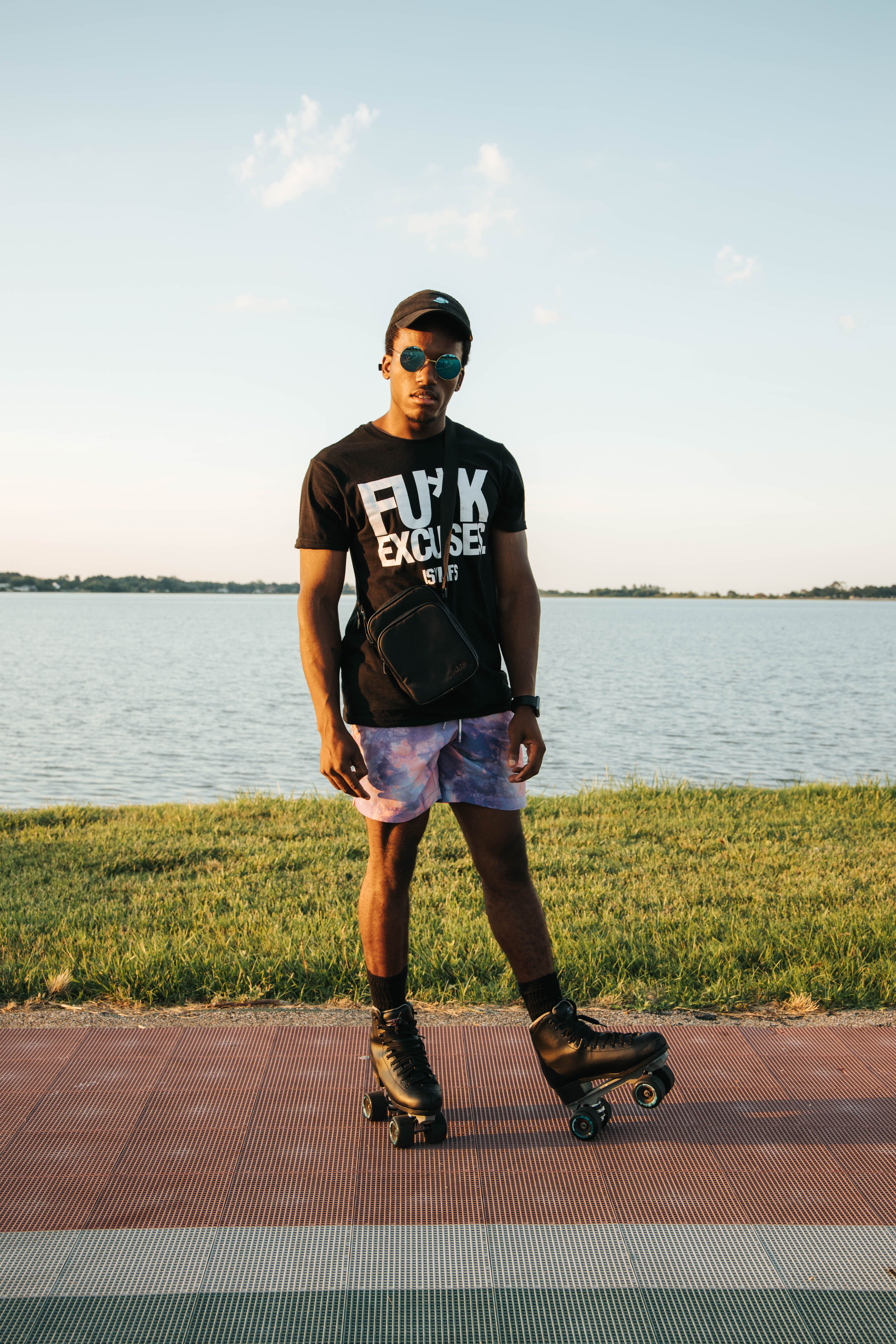 A stylish young man roller skates by a tranquil lake during sunset, capturing a casual outdoor moment.