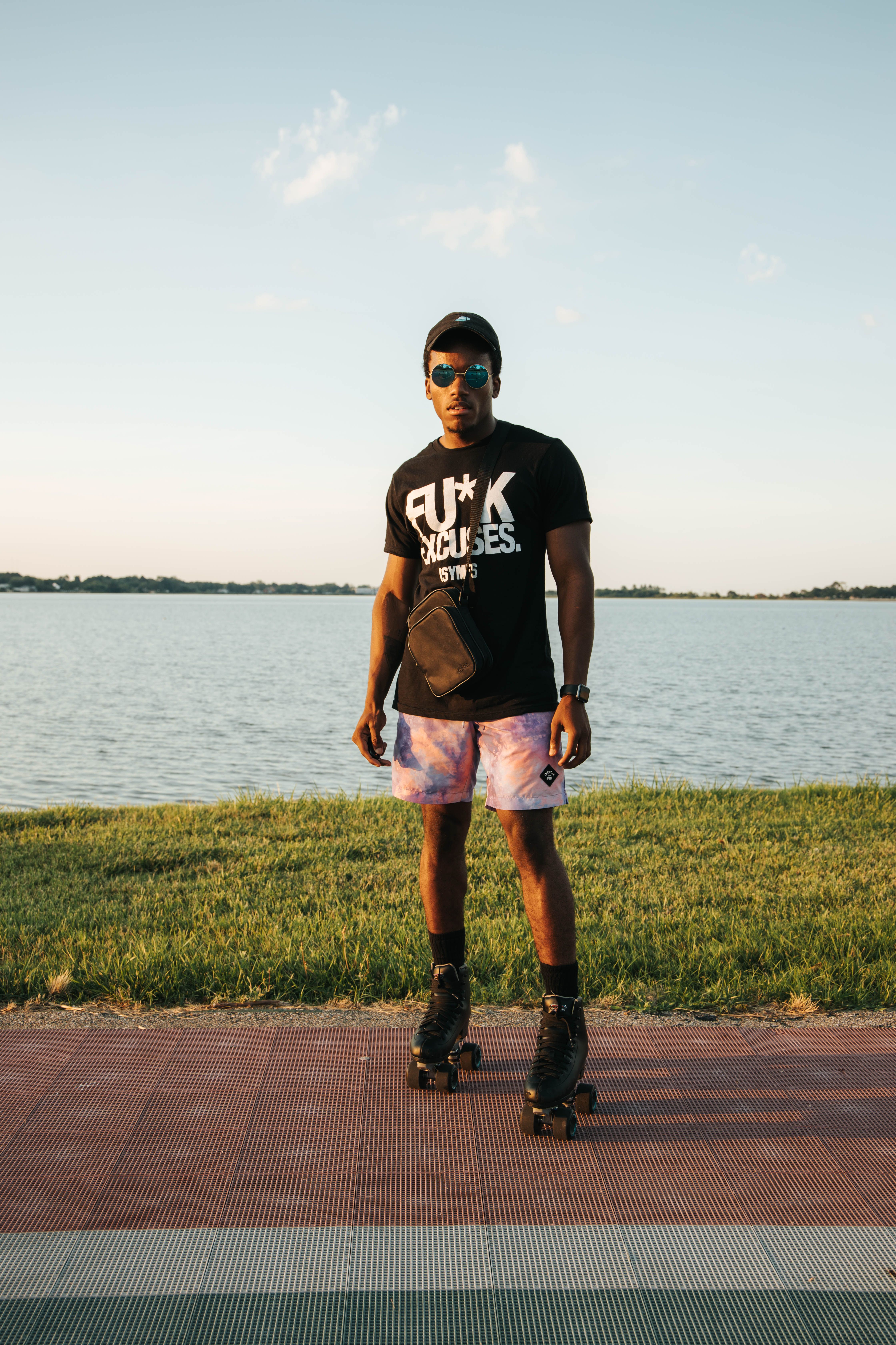 Young man roller skating by a serene lakeside during a bright summer day.