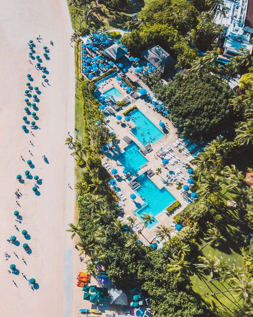 Photo by Jess Loiterton Stunning aerial view of a luxurious tropical resort with pools and beach access.
