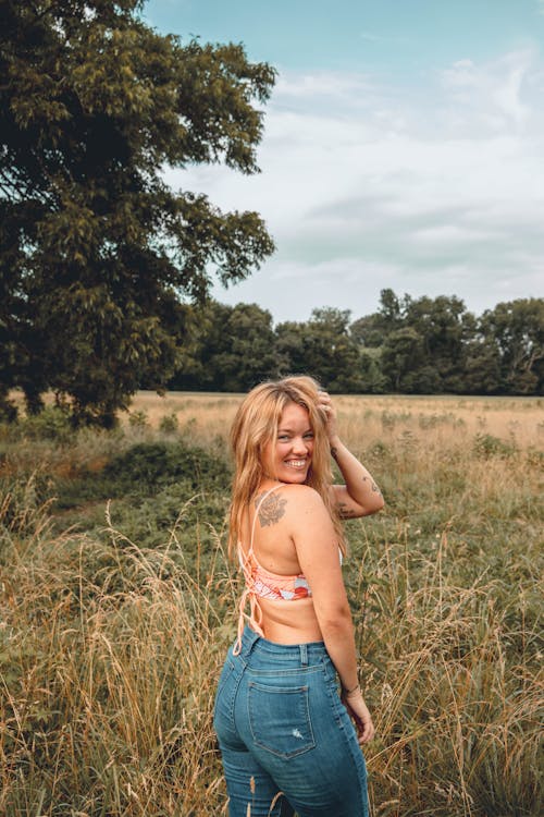 A Sexy Woman Standing on a Wheat Field while Smiling Beautifully on the Camera