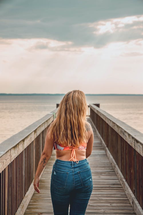 Back View Shot of a Woman Walking on the Wooden Dock