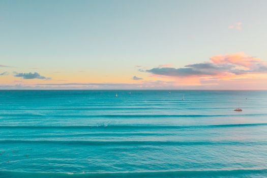 Stunning aerial view of the tranquil ocean during sunset in Waimea, Hawaii with peaceful waves and a serene sky.