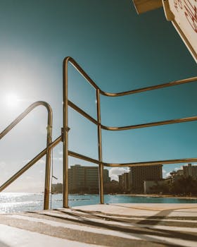 A sunlit view of railings overlooking the beachfront in Waimea, Hawaii, capturing urban coastal life.