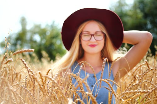 Free Woman Holding Her Cap on Her Head While Smiling Stock Photo