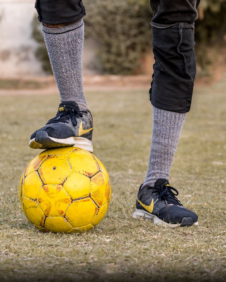 Unrecognizable Player Standing With Leg On Soccer Ball