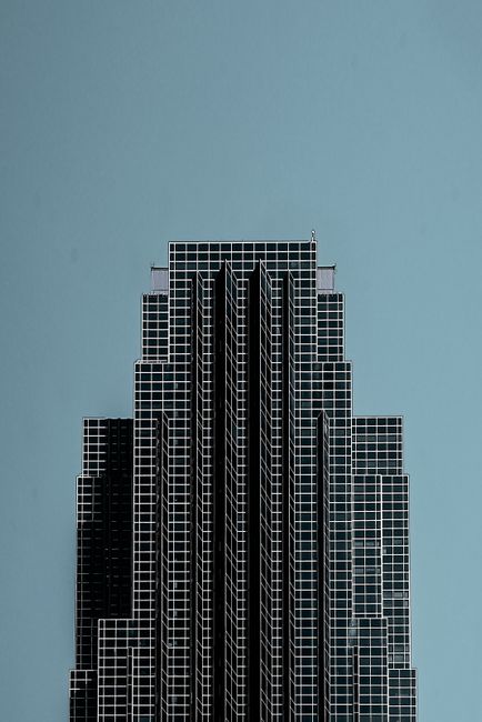 A modern skyscraper with a grid design stands tall against a clear blue sky in Houston.