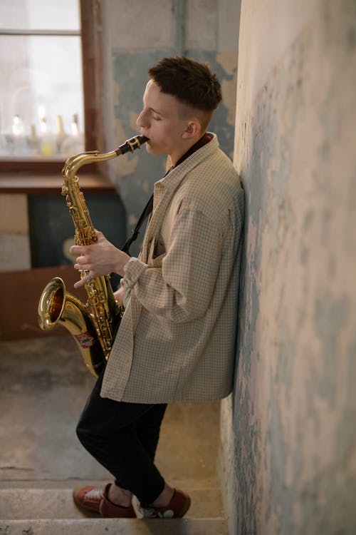 Man in Gray and White Checked Dress Shirt Playing Saxophone