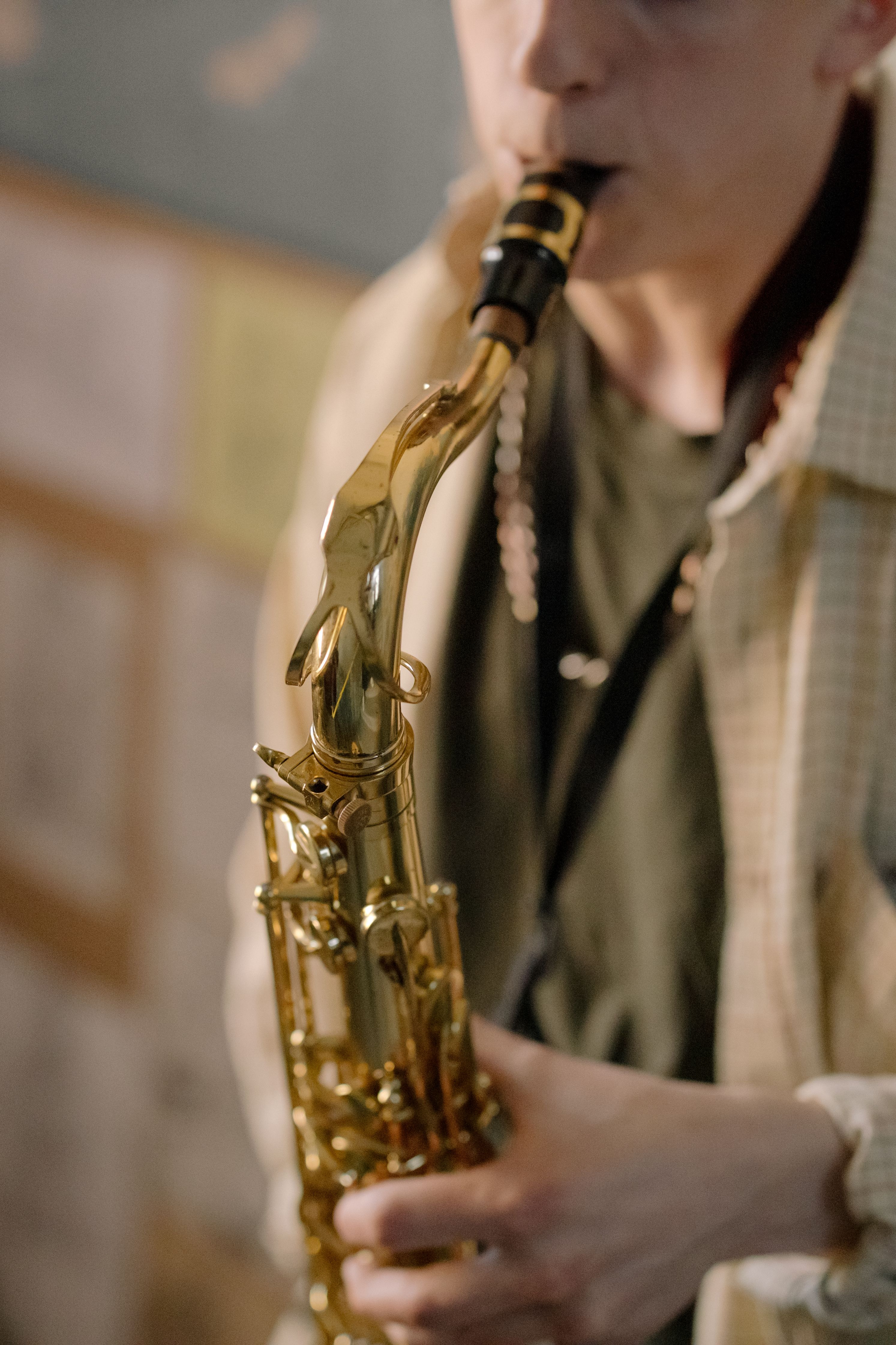 A young adult playing a golden saxophone indoors, showcasing musical talent and passion.