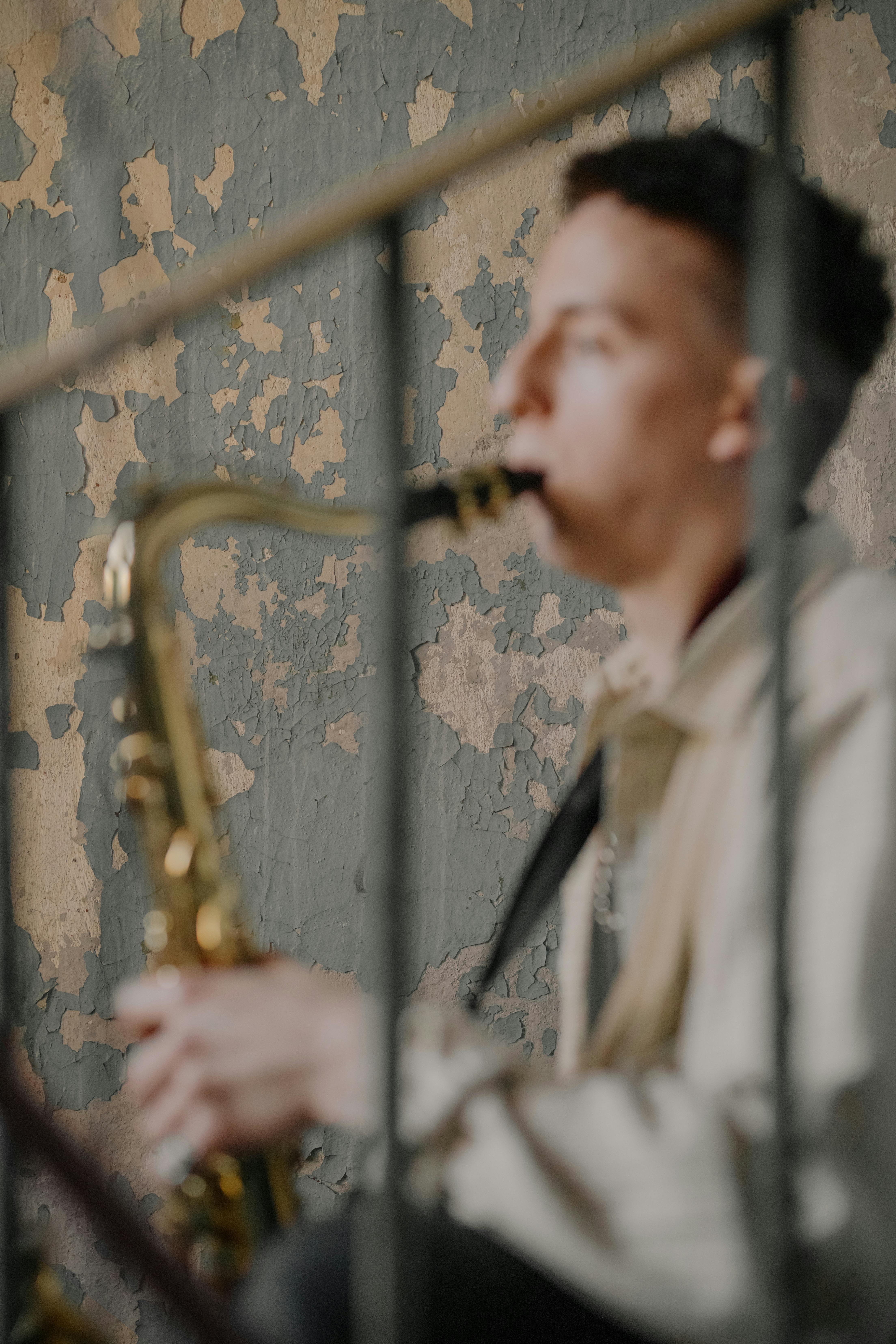 man in beige coat holding brass saxophone