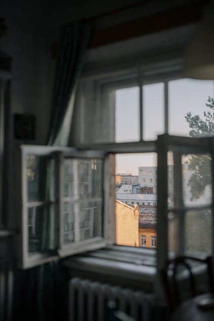 Interior room with an open window and city view, capturing the urban atmosphere.