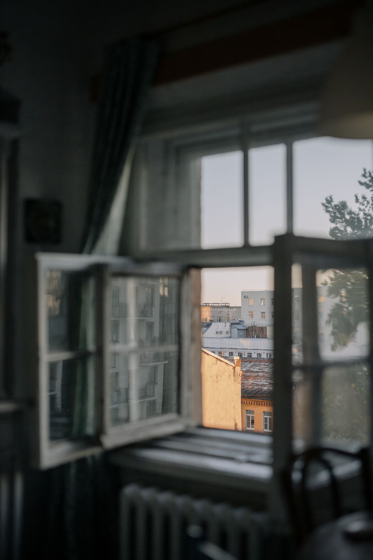 Weit geöffnetes Fenster in einem Wohnraum mit Blick über die Stadt, Sinnbild für Stoßlüften im Sommer