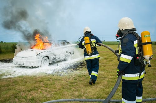 Free Deux Pompiers Pulvérisant Sur Un Véhicule En Flammes Stock Photo