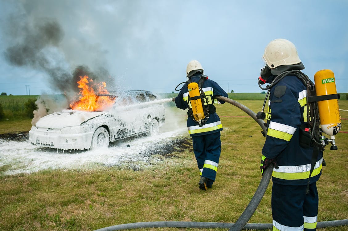бесплатная Пожарные распыляют на пылающий автомобиль Стоковое фото