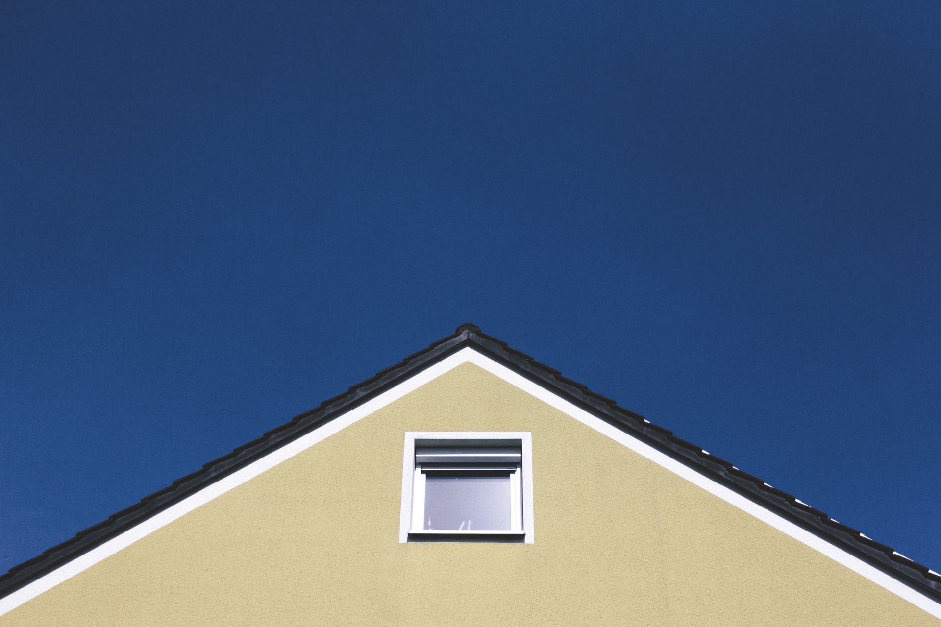 The Attic Window of a House under a Blue Sky
