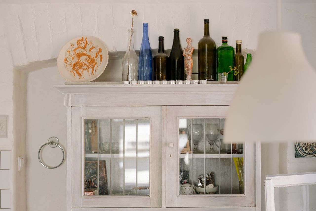 an interior view of a kitchen with vintage decor and glass bottles on