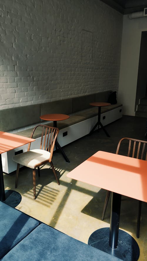 From above stylish minimalistic design of contemporary loft style cafe with tables and chairs against white brick wall
