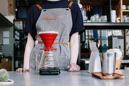 Barista in apron making pour over coffee with v60 dripper in modern coffee shop.