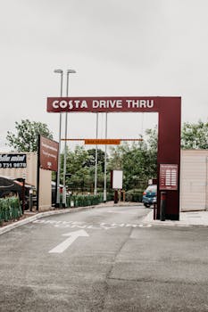 A drive-thru coffee shop entrance featuring prominent signage and clear direction markings.