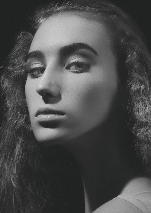 Free Grayscale portrait of a young woman with curly hair in dramatic lighting. Stock Photo