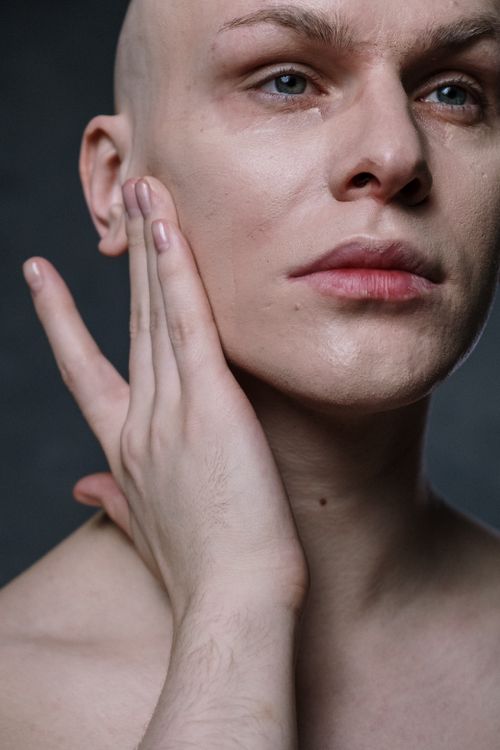 Free Intimate close-up of a bald man applying skincare product on his face, showcasing smooth complexion and grooming routine. Stock Photo