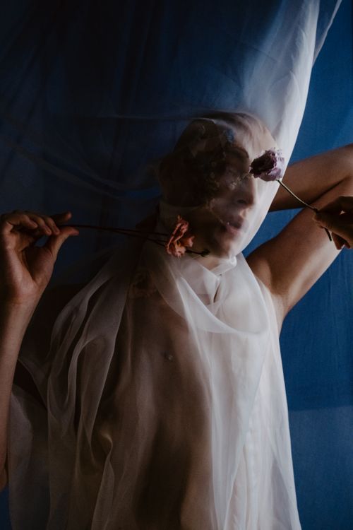 Free Artistic portrait of a person behind a veil holding flowers, exuding a dreamy and ethereal vibe. Stock Photo
