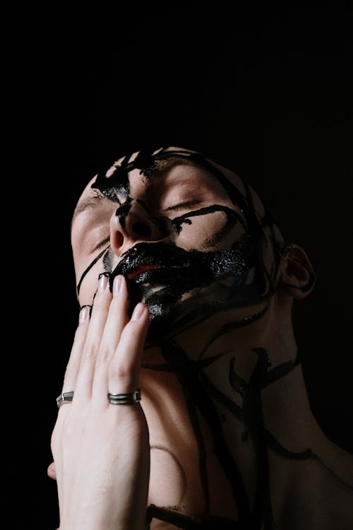 Woman in White Shirt Covering Her Face With Black and White Skull Mask