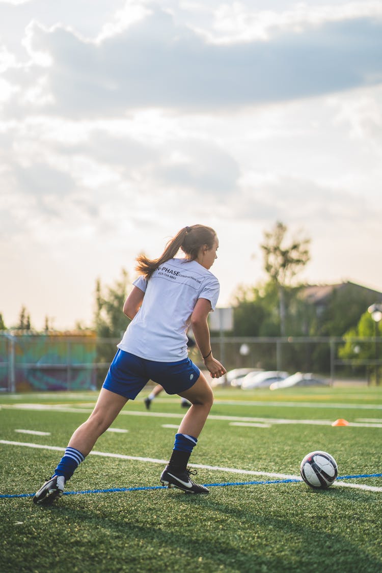A Woman Playing Soccer In The Field