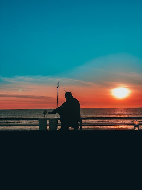 Silhouette Of Man Fishing On Seaside At Sunset · Free Stock Photo